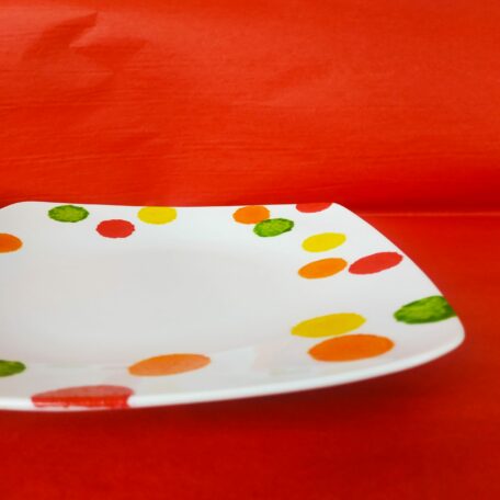 Vue à plat grande assiette plate carrée en porcelaine blanche peinte à la main, décor gros pois 