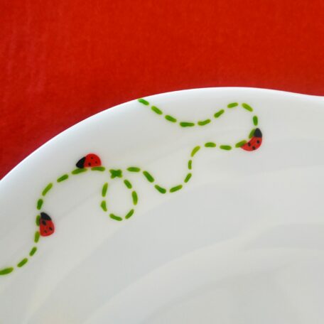 Détail grande assiette à dessert forme fleur, en porcelaine blanche peinte à la main, décor coccinelles