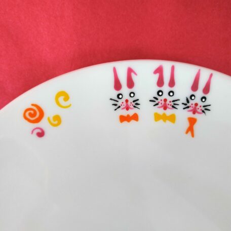 Détail assiette à dessert extra plate en porcelaine blanche peinte à la main, décor lapins roses